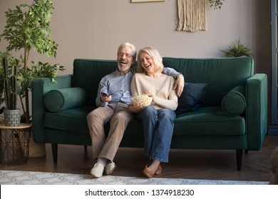 Happy Aged Couple, Wife And Husband Watching Tv, Comedy Movie And Eating Popcorn Snack, Laughing, Sitting On Cozy Couch At Home, Mature Family, Man And Woman Enjoying Free Time, Weekend Together