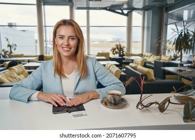 Happy Airline Passenger Seated In Airport Cafe