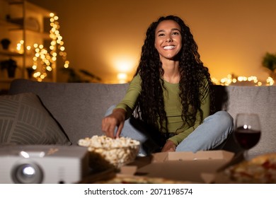 Happy Alone. Millennial Woman Watching Film Online Eating Popcorn And Drinking Wine Enjoying Movie Night At Home On Weekend, Sitting On Sofa In Living Room. Modern Lifestyle Concept