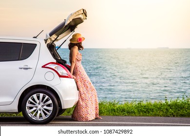 Happy Alone Young Woman Traveler On The Beach Road With White Hatchback Car And Sea Beach Background. Traveler Car Concept