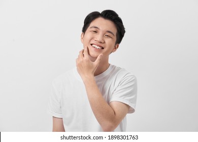 Happy and amazed asian young man touching his face, shocked with unexpected promotion on white background