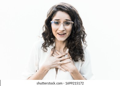 Happy amazed woman in glasses gasping and applying hands to chest. Wavy haired young woman in casual shirt standing isolated over white background. Surprise concept - Shutterstock ID 1699215172