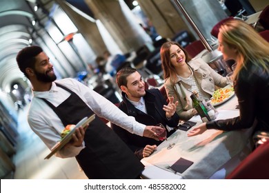 happy american afro waiter taking table order and smiling in winter evening