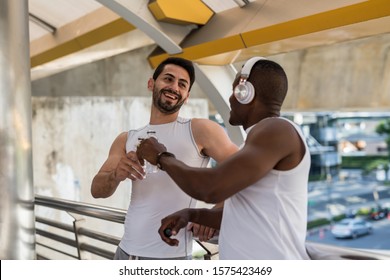 Happy American Bearded Man With African Black Friend Toast And Drink Water After Running Workout In Modern City. Bodybuilding And Healthy Lifetstyle. Lovely LGBT Gay Couple Exercise.