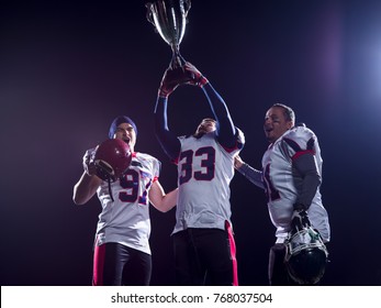 happy american football team with trophy celebrating victory on night field
