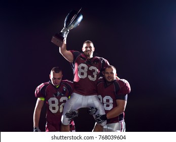 Happy American Football Team With Trophy Celebrating Victory On Night Field