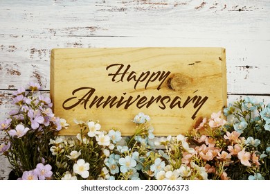 Happy Anniversary text message with flower decoration on wooden background - Shutterstock ID 2300766373