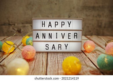 Happy Anniversary Text On Lightbox On Wooden Background