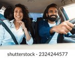 Happy arab couple going on summer vacation by car, man and woman sitting in their new auto, cheerfully smiling looking at road, making test drive in the city