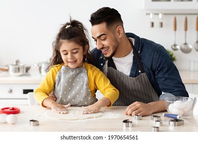Happy arab father and little daughter baking together in kitchen, making dough for pizza or cookies, loving middle eastern family dad and child preparing pastry, enjoying cooking at home, copy space - Powered by Shutterstock
