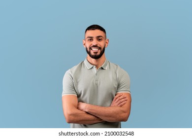 Happy arab guy smiling to camera, crossing hands and posing over blue background, studio shot. Excited self-confident middle eastern man expressing positive emotions - Shutterstock ID 2100032548