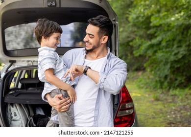 Happy Arab Man Holding Son In Arms And Playing With Him Near Car With Open Trunk Outdoor In Summer. Family Travel, Vacation Together And Auto Journey At Free Time, Picnic Outside In Park, Copy Space