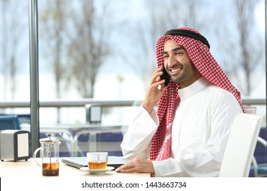 Happy Arab Man Talking On Smart Phone Sitting In A Coffee Shop