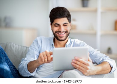 Happy Arab Man Using Digital Tablet, Shopping Online, Browsing Internet Or Working Remotely On Tab Computer