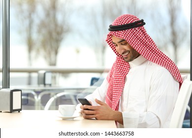 Happy Arab Man Using A Smart Phone Sitting In A Coffee Shop Interior