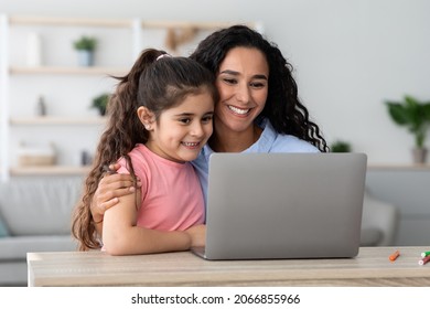 Happy Arab Mom And Little Daughter Using Laptop At Home Together, Smiling Young Mother And Her Female Child Looking At Computer Screen, Watching Movies Or Development Videos For Kids, Closeup