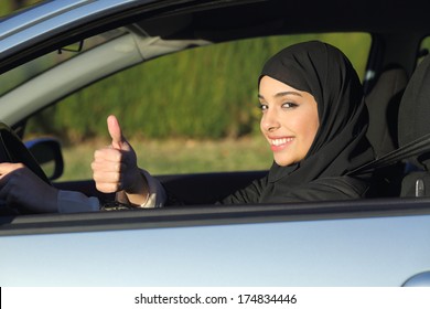 Happy Arab Saudi Woman Driving A Car With Thumb Up Smiling With A Headscarf    