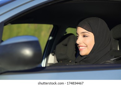 Happy Arab Saudi Woman Driving A Car Smiling With A Headscarf