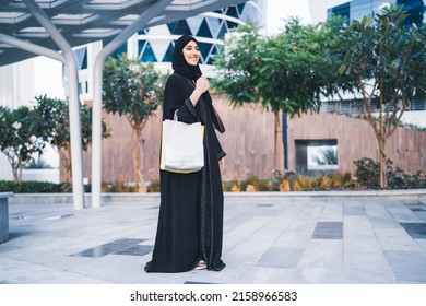 Happy Arab woman shopping carrying bags. Arabian Muslim lady excited in sale wearing abaya outdoor in mall