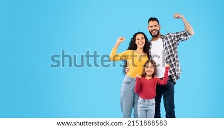 Happy Arabic Family Showing Biceps Smiling To Camera Standing Over Blue Studio Background. We Are Strong, Strength And Power Concept. Panorama With Copy Space