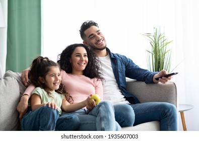 Happy arabic family of three relaxing and watching tv at home