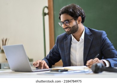 Happy arabic indian young business man executive manager, office employee or teacher wearing suit working on laptop computer, online learning teaching on professional webinar, doing market research. - Shutterstock ID 2184784975