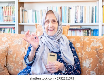 Happy Arabic Muslim Old Woman Wearing Earphone To Listen To Music From Her Smartphone