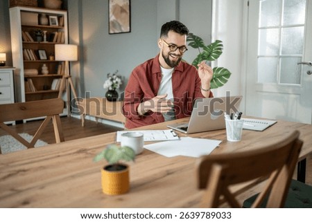 Happy architect gesturing while engaging in video conferencing on a laptop at a home office, working remotely and participating in an online meeting with clients and colleagues