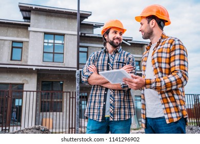 happy architects using digital tablet at construction site - Shutterstock ID 1141296902
