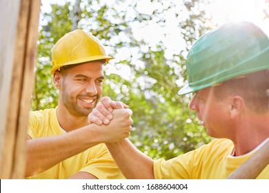 Happy artisans do teamwork on house building and hold hands