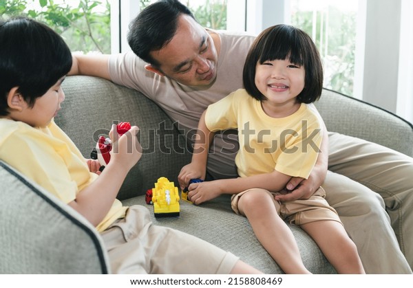 Happy Asia father\
with sons play toys in\
home