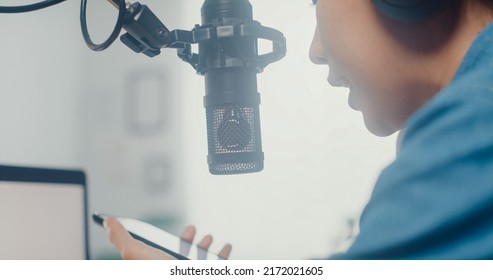 Happy Asia Girl Record A Podcast On Laptop Computer With Headphones And Microphone Talk With Audience At Living Room. Female Podcaster Make Audio Podcast From Her Home Studio. Close Up Shot.