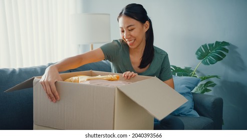 Happy Asia Lady Open Cardboard Box Package Exciting And Enjoy Trying And Matching With Quality Of Fashion Cloth Product From Online Market In Living Room At Home. Online Shopping And Delivery Concept.