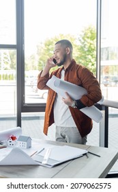 happy asian architect with rolled blueprints talking on smartphone in office - Shutterstock ID 2079062575