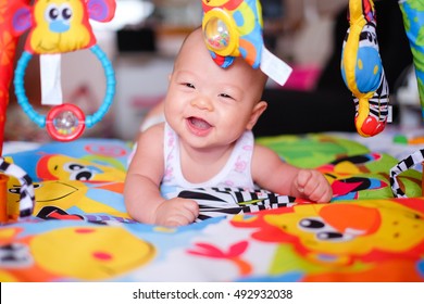 A Happy Asian Baby Boy At Tummy Time On The Play Gym On Bed In Bedroom At Home - Selective Focus