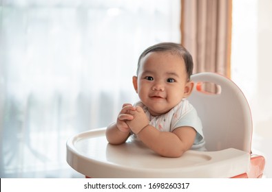 Happy Asian Baby Feeding Time Sitting On Highchair