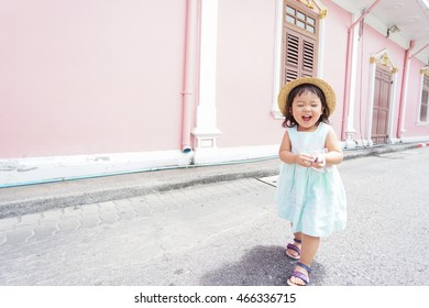 Happy asian baby girl walking on old town street in Phuket Thailand.