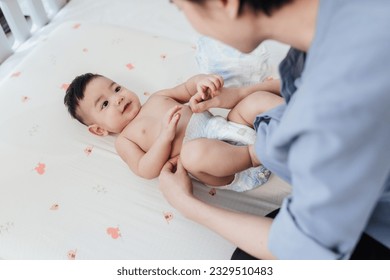 Happy Asian baby shirtless lying on bed is changing diaper by his mother. Baby healthcare hygiene concept. - Powered by Shutterstock