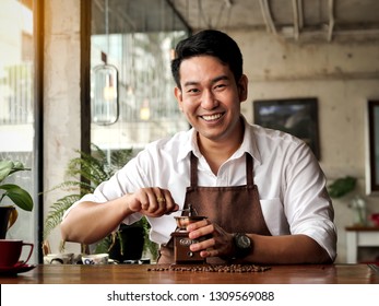 Happy Asian Barista Man Grinding Coffee Beans On Table, Lifestle Concept.