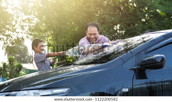 Happy\
Asian boy help parent washing car on water splashing with sunlight\
at home, Slow Motion. Activity holidays in\
family.
