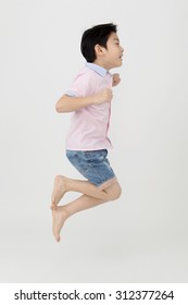 Happy Asian Boy Is Jumping At Studio On Gray Background,Shoot On Right Side