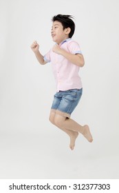 Happy Asian Boy Is Jumping At Studio On Gray Background, Shoot On Leftt Side