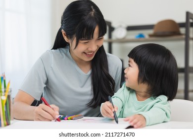 Happy asian boy painting and crayon   colored pencil and his mother in living room at home  Mom teaching son how to painting and crayon color book doing homework  family concept 