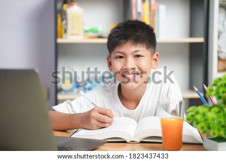 Happy Asian boy student online learning with laptop at home. class study online video call. Social distance, home schooler, New normal, Covid-19, Stay home.