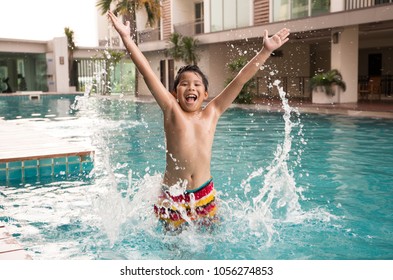 Happy Asian Boy In Swimsuit Enjoy Jumping In A Swimming Pool With Beautiful Blue Water Splash