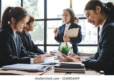 Happy Asian Business Colleagues Brainstorm At Conference Table Discuss Project At Meeting, Elderly Business Woman Boss Talk Negotiating In Office At Briefing.