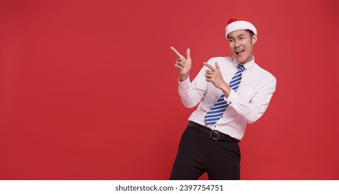 Happy asian business man wearing santa hat pointing finger isolated on red copy space background. advertising christmas day - Powered by Shutterstock