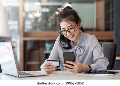 Happy Asian Business Woman Pay Online Using Mobile Phone At The Office.