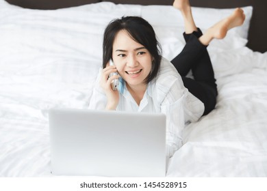 Happy Asian Business Woman Talking With Cell Phone Laying Down On The Bed.