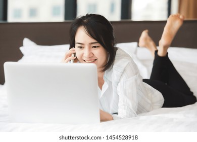 Happy Asian Business Woman Talking With Cell Phone Laying Down On The Bed.